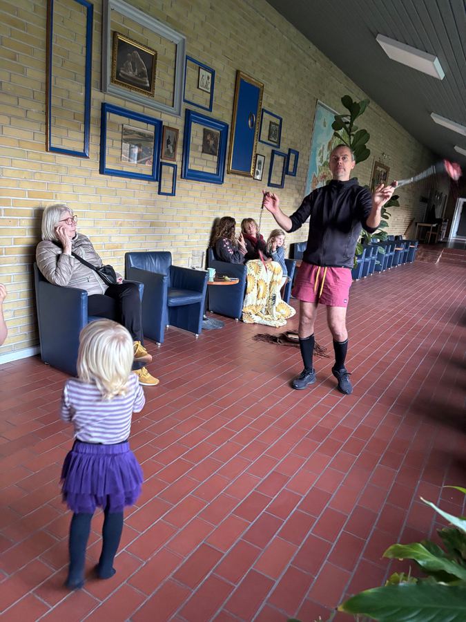 Jonglering med pinde indendørs, mens et barn ser med